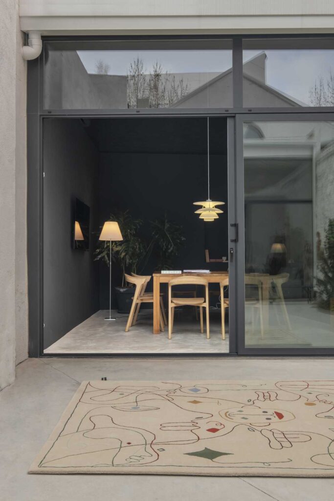 Tappeto Nanimarquina Silhouette Outdoor posizionato tra interno ed esterno, con design ricamato di Jaime Hayón.